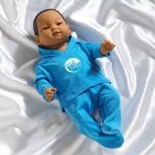 baby doll wearing a green onesie on a white blanket